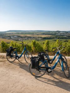 Electric bicycles parked beside vineyards overlooking the Champagne countryside in France.