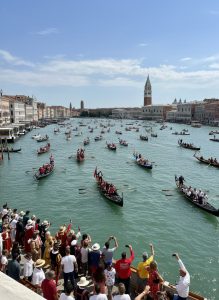 Gondolas and traditional boats filling the Grand Canal during the Festa del Redentore with crowds watching from the waterfront.