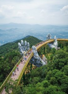 The Golden Bridge stretches above the forests of Ba Na Hills near Da Nang, supported by its iconic giant stone hands.
