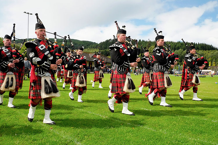 highland-games-pipe-band-scotland Pipe band marching at a traditional Scottish Highland Games