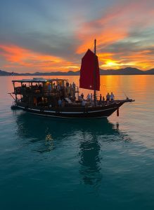 Traditional sailing vessel cruising across calm waters at sunset near Hua Hin, Thailand.