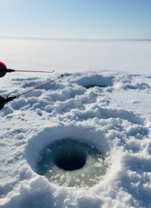 Ice fishing hole cut through the snow on a frozen lake in Norway