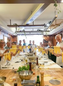 Guests proudly holding freshly made pasta during a hands on Italian cooking class.