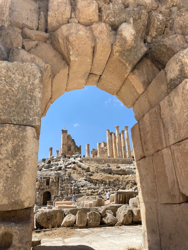 Ancient stone arch framing the Roman ruins of Jerash in Jordan.