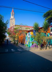 Colourful street in Lima's Barranco district with murals, tropical trees and historic church tower