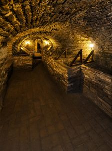 Visitors exploring the historic brick lined catacombs beneath San Francisco Convent in Lima, Peru.