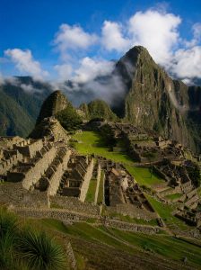 Panoramic view of the ancient Inca citadel of Machu Picchu surrounded by cloud covered Andean peaks.