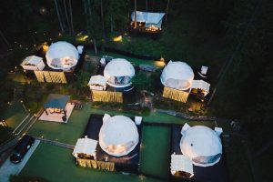 Aerial view of illuminated glamping domes surrounded by forest in Kawaguchiko, Japan