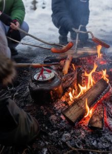 Sausages roasting over a Norwegian bonfire in a snowy winter setting