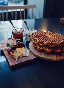 Traditional Norwegian waffles served with jam, cream, cheese, and fresh berries in a cosy café in Oslo