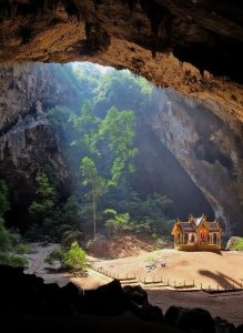Sunlight streaming into Phraya Nakhon Cave, illuminating the royal pavilion beneath towering limestone walls in Thailand.