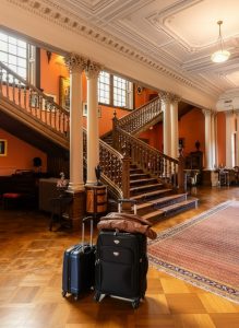 Guests depart from a grand Scottish country house hotel with luggage in the entrance hall.