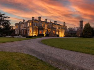 Historic Scottish country house hotel illuminated at sunset with sweeping driveway.