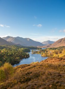 Rolling hills, forests and lochs in the Scottish Highlands.