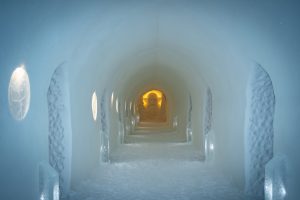 Ice carved corridor inside the Sorrisniva Ice Hotel in Alta, Norway, illuminated by soft Arctic lighting.