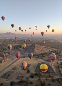 Colourful hot air balloons floating above the Pyramids of Teotihuacán at sunrise in Mexico.