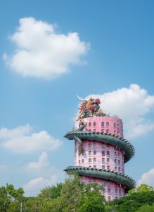 The pink tower of Wat Samphran wrapped by a giant dragon sculpture rising above the surrounding countryside.